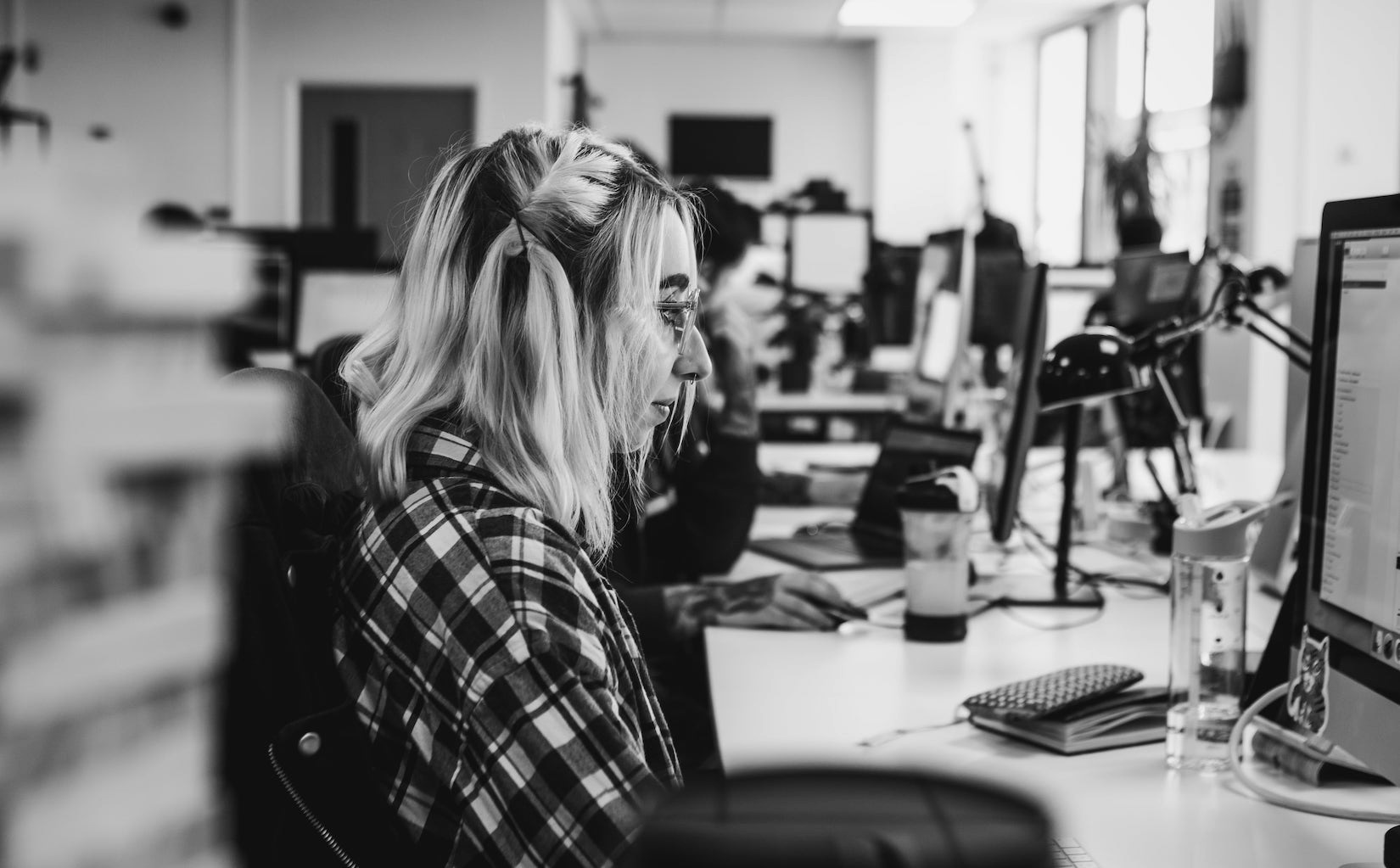 A black and white photograph of Frameworks’s UI/UX designer working on a computer, taken from the side.